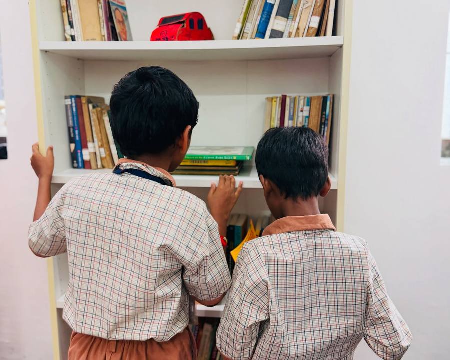 Two school children at a newly built classroom bookshelf