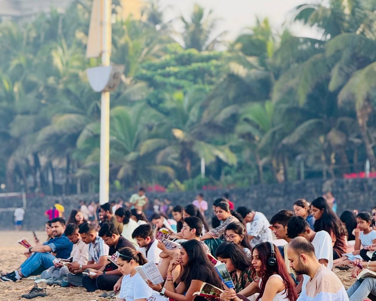 Hundreds of readers seated on a Mumbai beach at sunrise