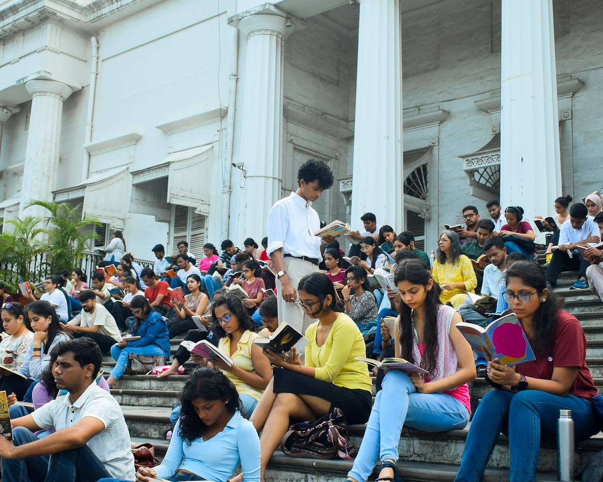 A crowd of readers on the steps of a colonnaded Mumbai monument
